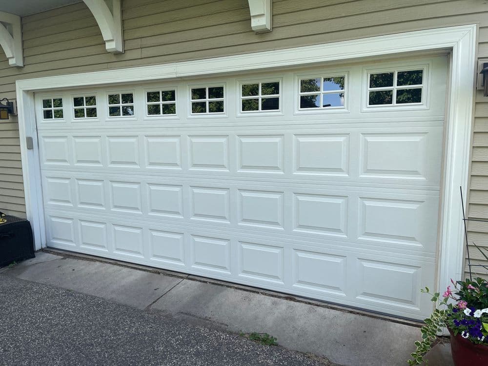 White garage door with decorative windows, installed on a suburban home.