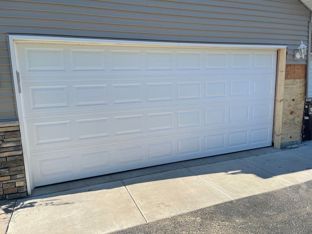White garage door on a residential home with beige siding and stone accents.