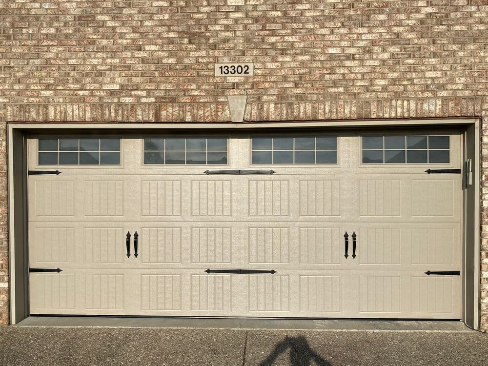 Tan garage door with vertical panels, decorative hardware, and address "13302" displayed above.