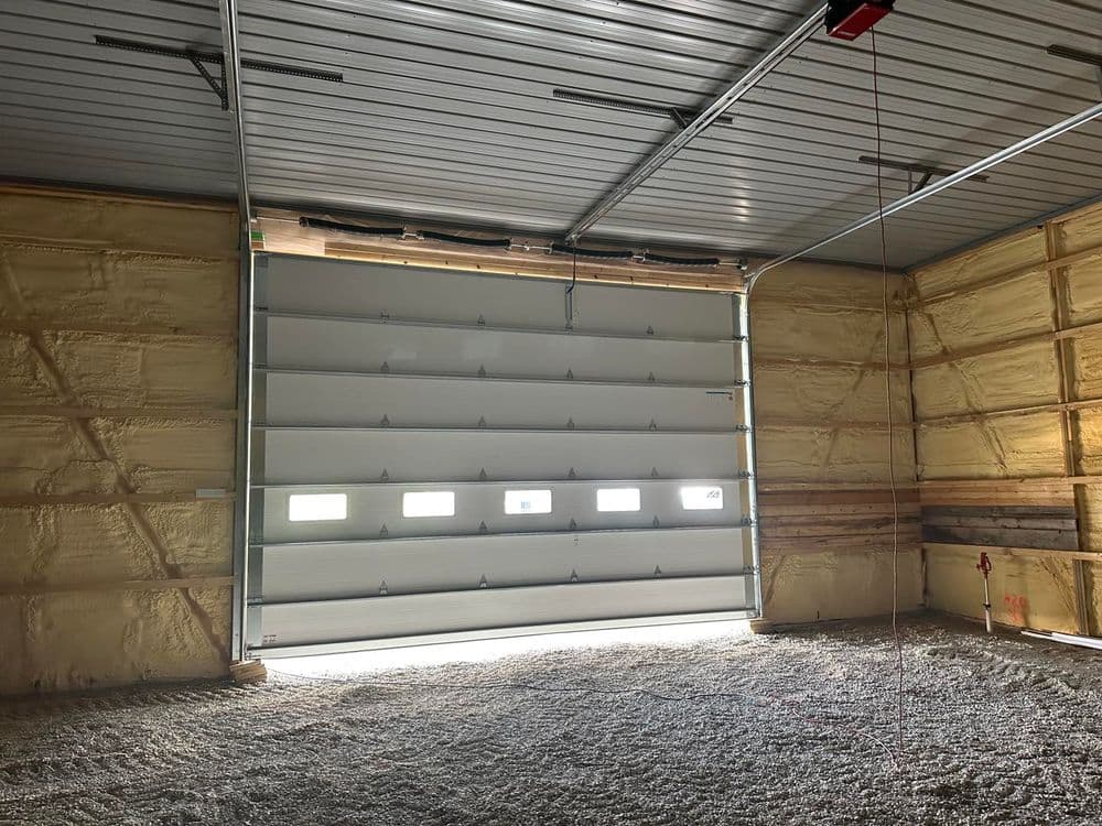 Interior of a spacious garage with a large roll-up door and insulated walls.
